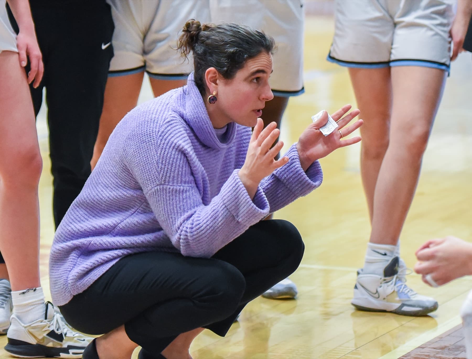 Jill Pace leading a team huddle courtside